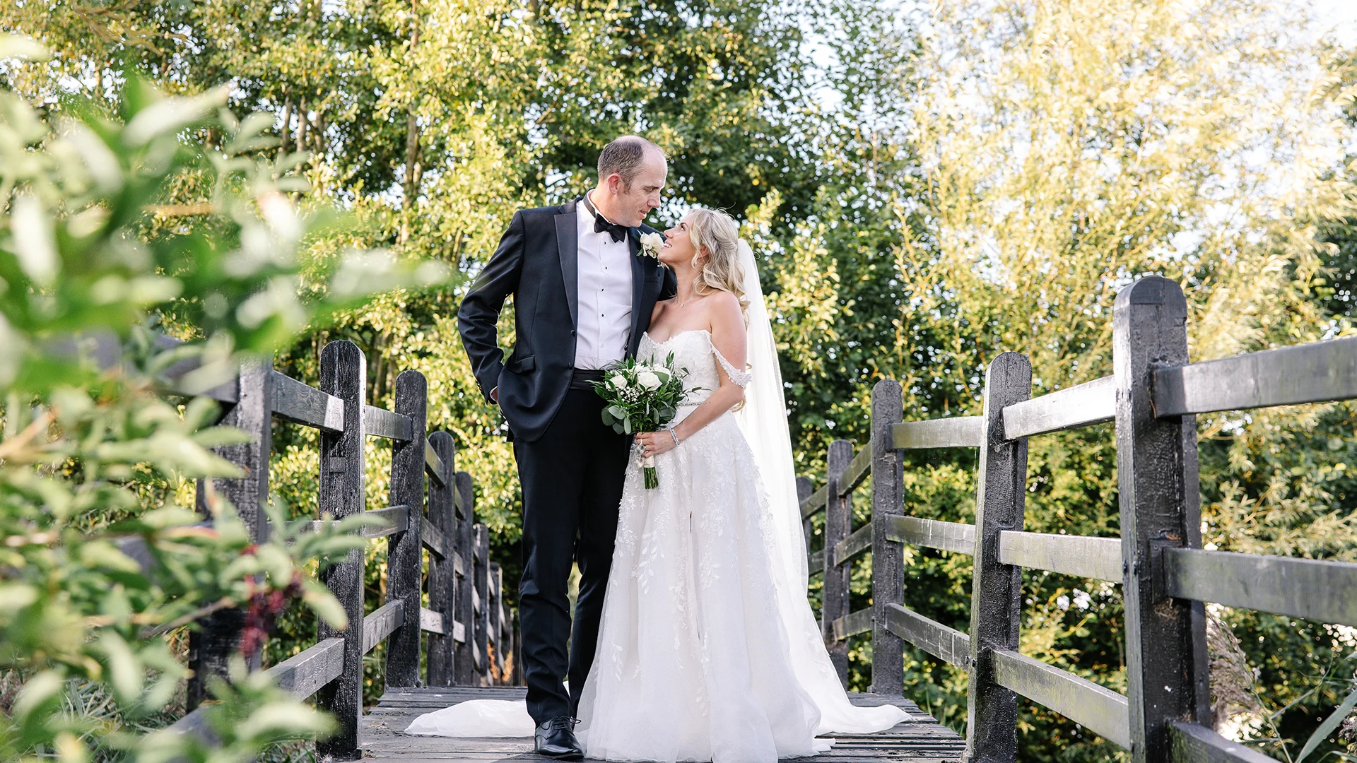Blog 14 A newlywed couple sharing a romantic moment by the historic moated bridge, highlighting the breathtaking Wedding Photography Locations Essex available at Prested Hall.