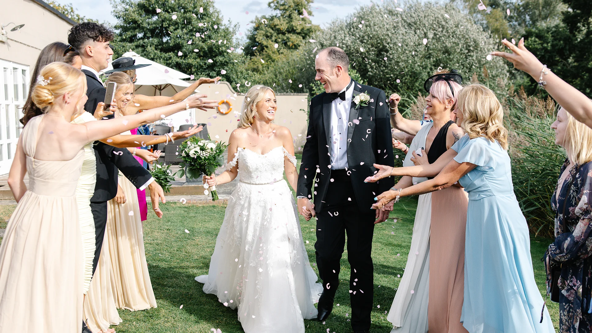 Blog 9 An elegant bridal party walking across a historic moated bridge, showcasing the breathtaking scenery of a premium UK destination wedding venue.